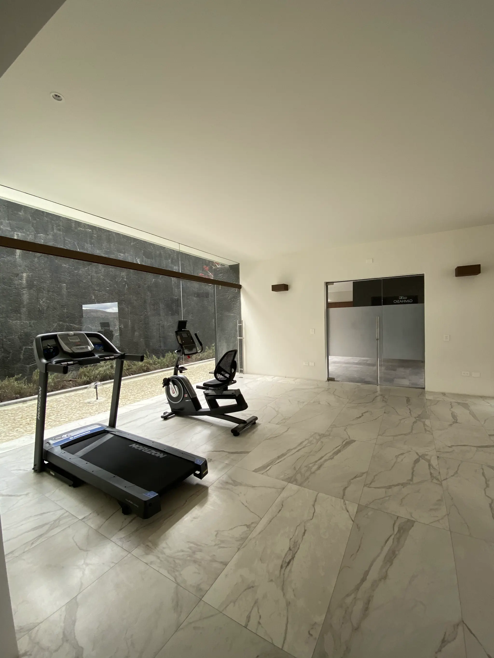 Gimnasio de la Casa Club de Vedana con muro de piedra volcánica